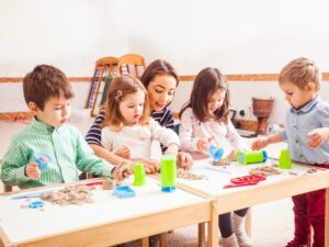 Structured indoor activities in daycare help develop a child's social skills through collaborative sensory play with sand.