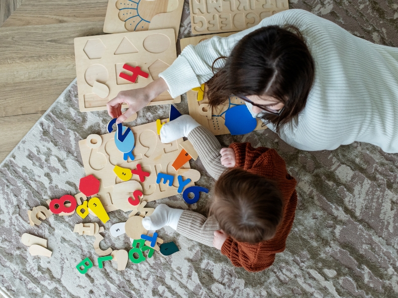 Mother and child playing with educational toys, showcasing personalised care plans for individual child development.