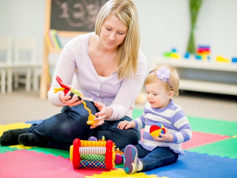 Caregiver and infant enjoying interactive daycare activities for infants, promoting learning through vibrant toys and hands-on exploration.