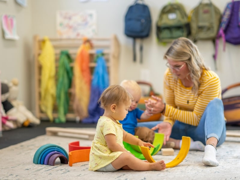 Teacher engaging in sensory daycare activities for infants, using colourful toys to enhance toddler development and curiosity.