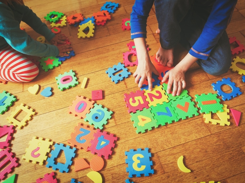 A teacher and child working on a puzzle, demonstrating the benefits of early childhood education on cognitive development.