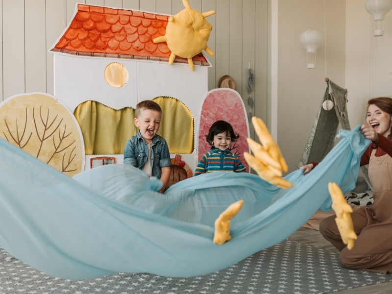 Toddlers happily playing, learning emotional regulation strategies through play-based activities and social interaction.