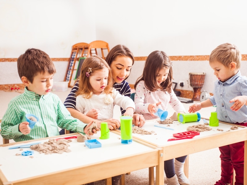 A daycare teacher guiding children with hands-on activities, illustrating supportive daycare transitions for kids.