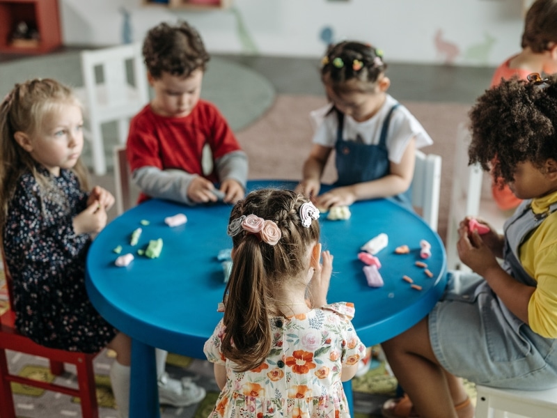 Children engage in play-based learning, participating in cognitive activities for preschoolers around a table.