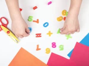 Child playing with numbers and fine motor skills boosted through colourful preschool readiness activities.