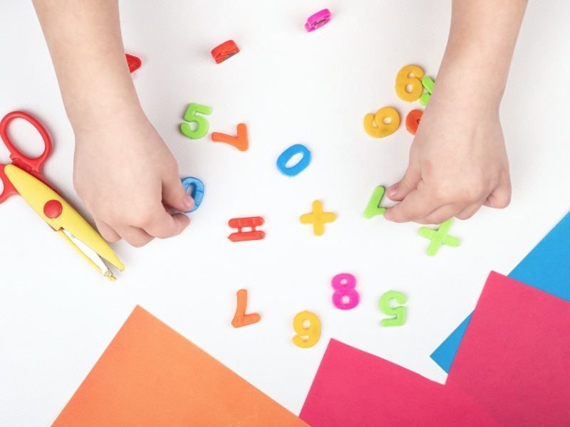Child playing with numbers and fine motor skills boosted through colourful preschool readiness activities.